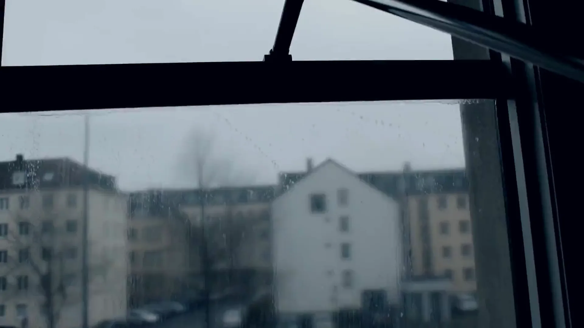 Blick aus einem Bürofenster auf eine Straße mit Bushaltestelle, während ein Abzieher die Scheibe klar zieht